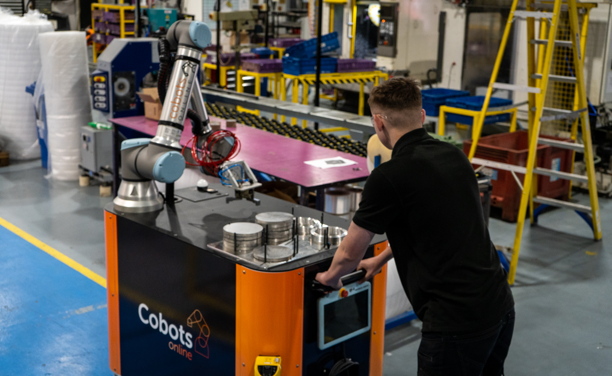 worker pushing CoboTend cobot unit on factory floor