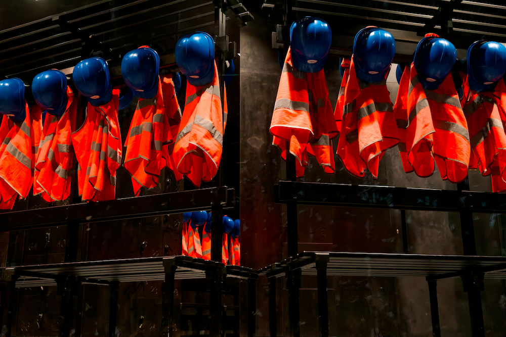 hard hats and high vis vests hanging up on wall